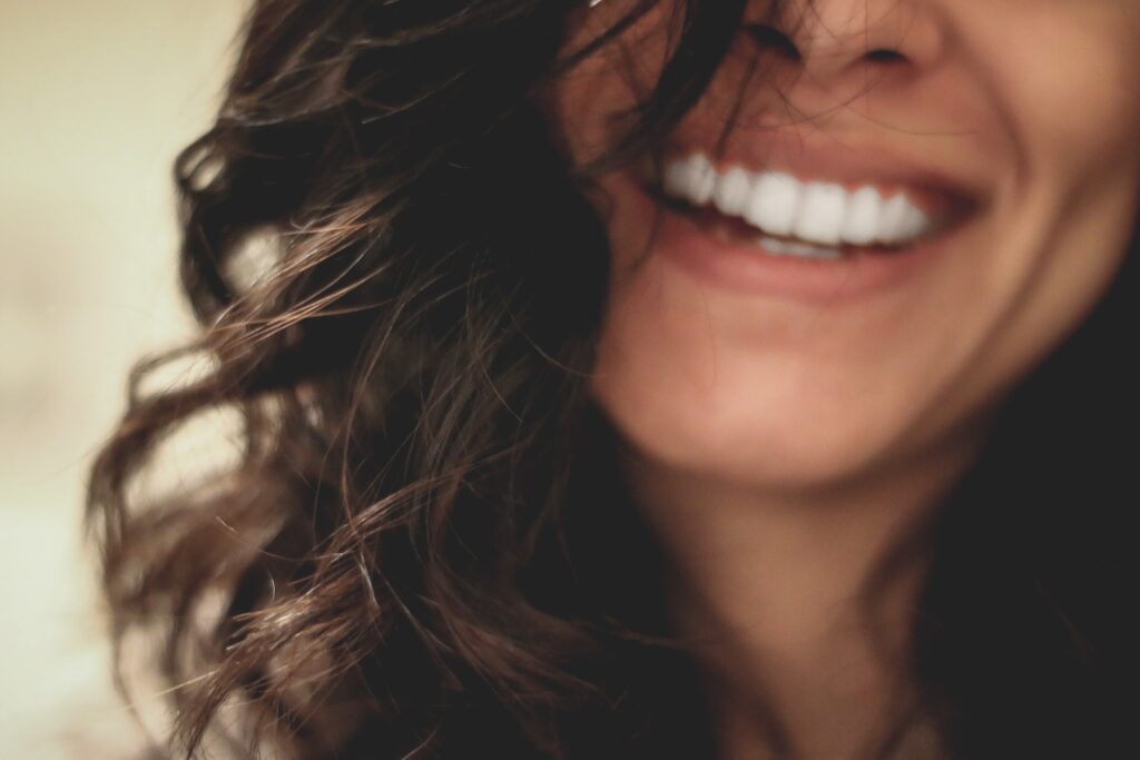 Woman with long, dark hair smiling joyfully.