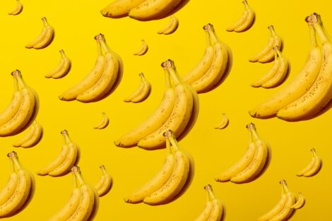Bunches of variously-sized yellow bananas on a yellow background.