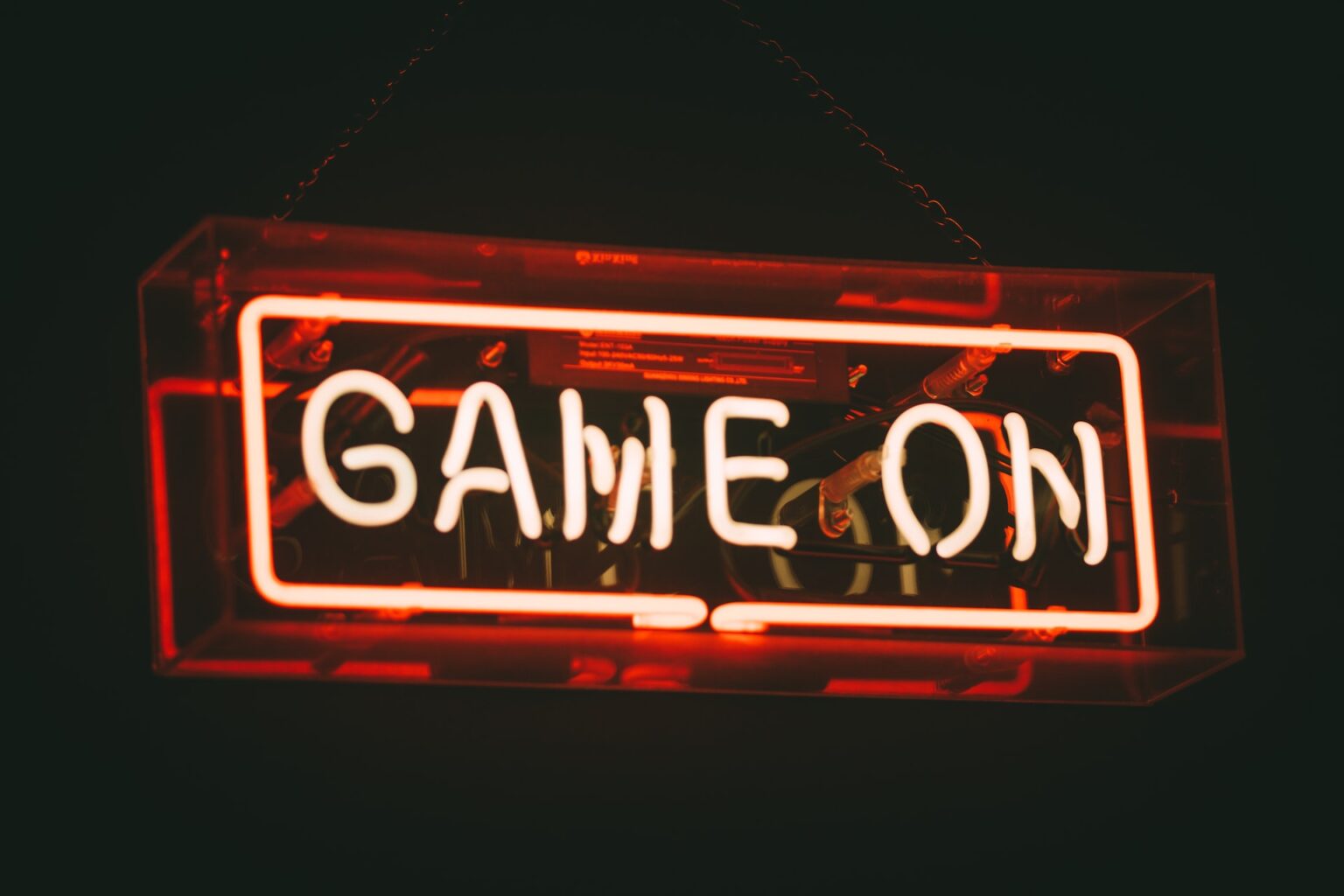 Neon sign reading “game on” in red and white against black background.