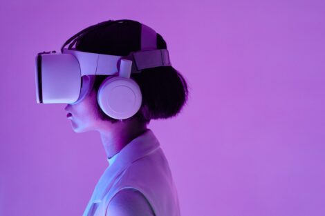 Woman wearing virtual reality goggles in room with lilac lighting.