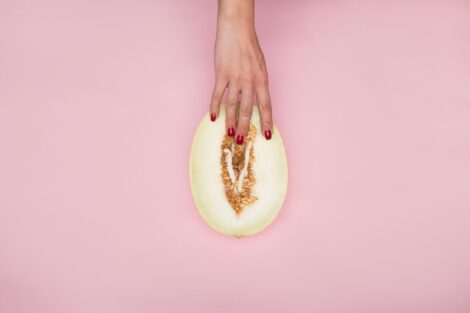 Woman’s fingers with nails painted red, caress a halved honeydew melon.