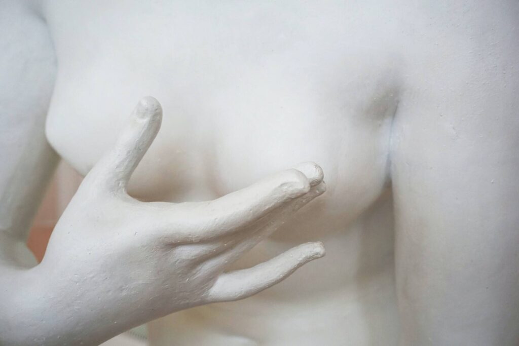 Close up of plaster statue with finger caressing own nipple.
