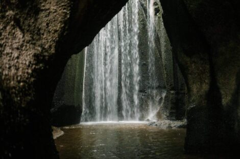 Waterfall inside rocky ravine, lit by sun.