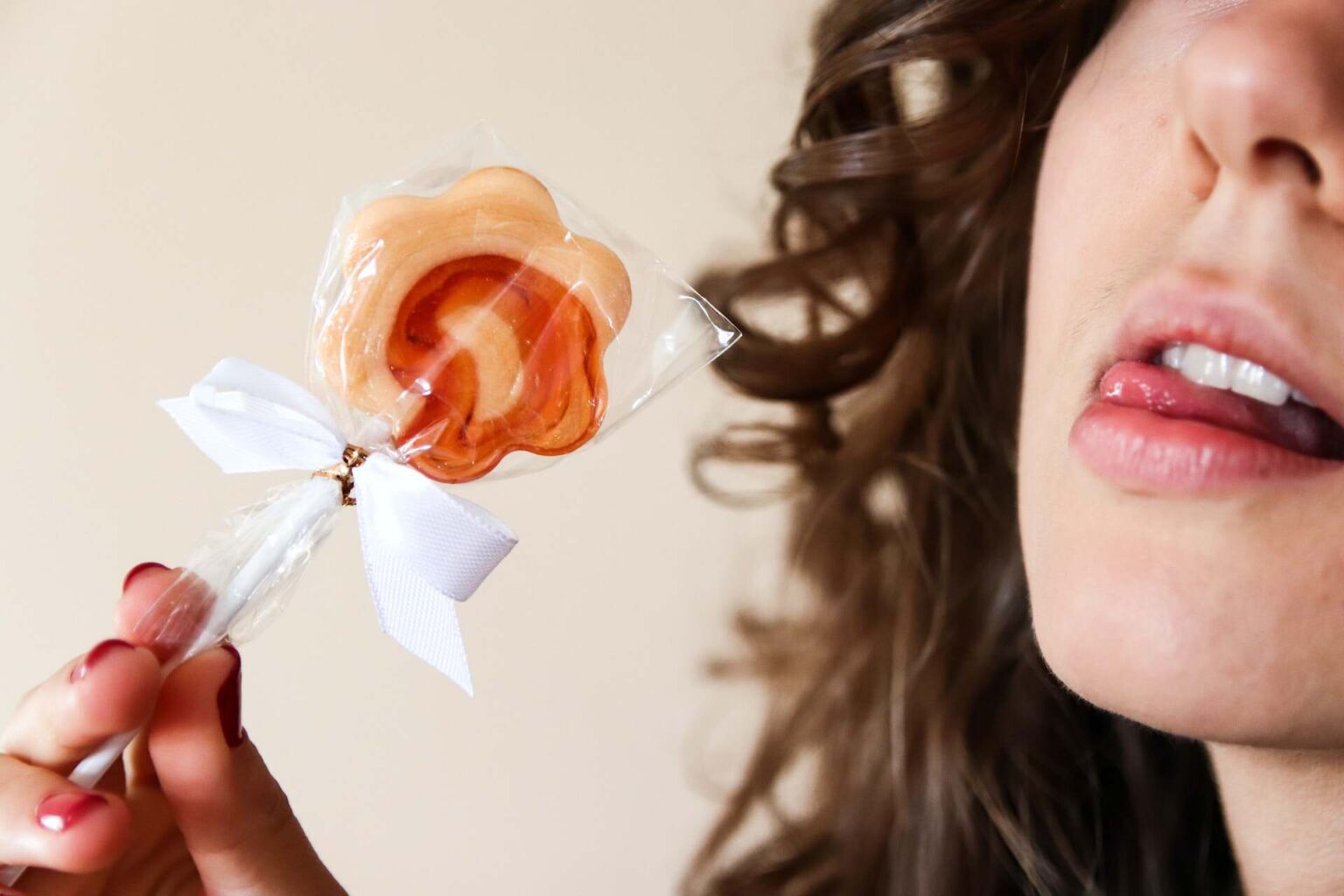 Woman licks lips, hoping rose-shaped lollipop.
