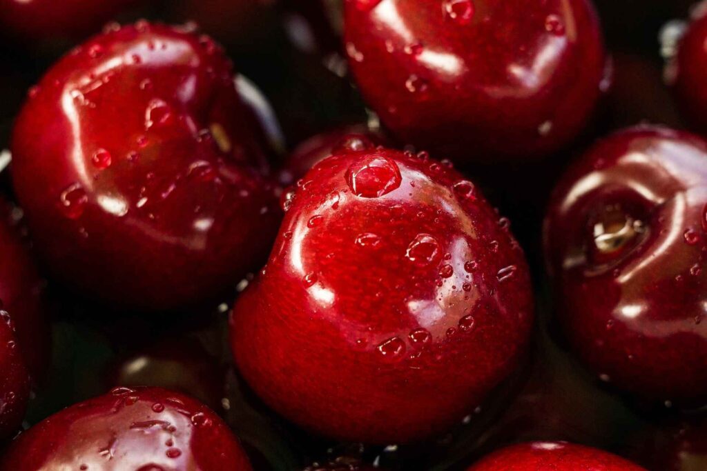 Recently washed, juicy red cherries with water droplets still clinging to them.